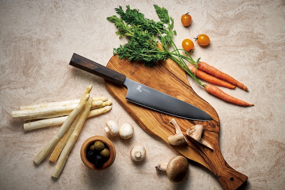 Japanilainen keittiöveitsi ja vihanneksia puisella leikkuulaudalla