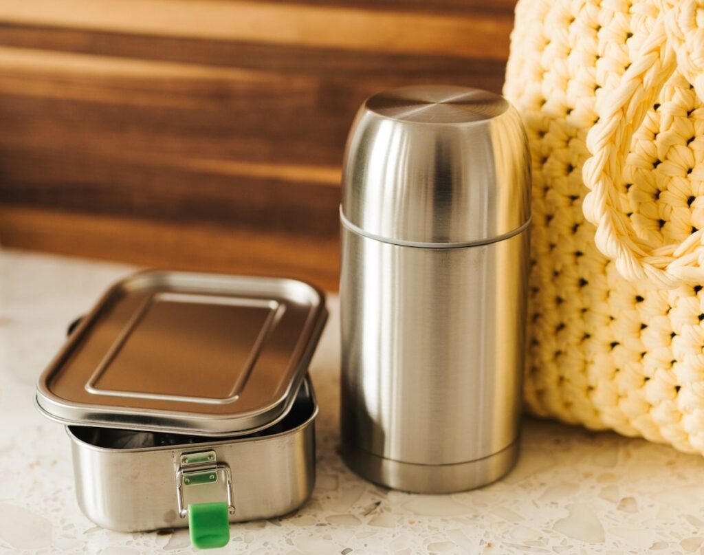 teräksinen ruokatermos ja eväsrasia pöydällä